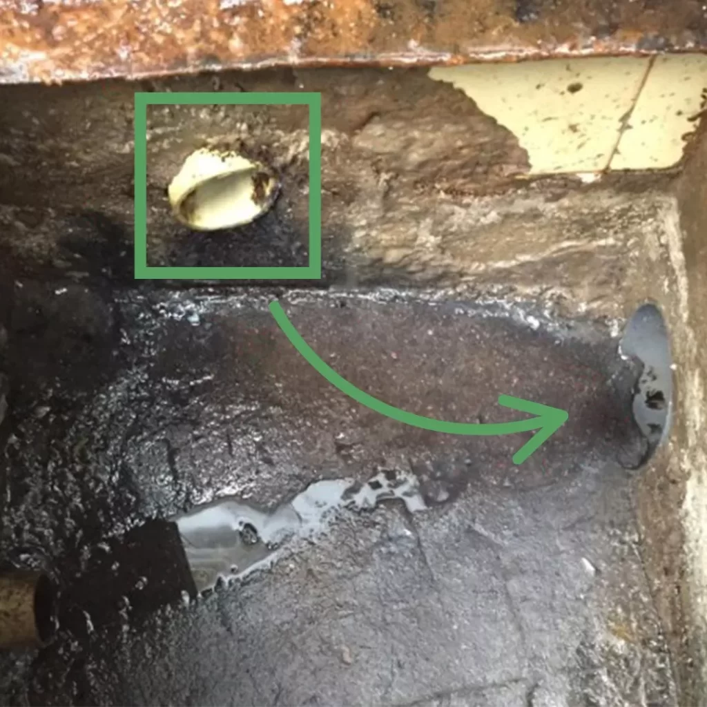 Trampa de grasa en campo con detalle señalado de una conexión de tubería mal posicionada.